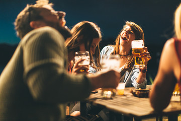 Group of friends drink beer on the terrace during summer night
