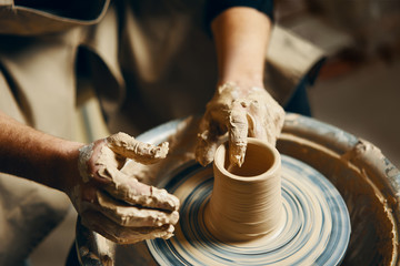 Potter modeling ceramic pot from clay on a potter's wheel