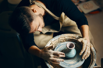 Potter modeling ceramic pot from clay on a potter's wheel