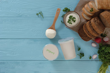Fototapeta na wymiar yogurt in a plastic container and bread on a blue wooden background, top view. healthy eating concept