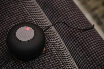 Small bluetooth speaker being charged on the couch close up view