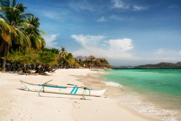 Tropical Malcapuya island with traditional philippines bangka boat, azure water and white sand beach. Travel vacation at Philippines.