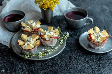 sweet muffins with yogurt and apples and tea on a dark, stone table