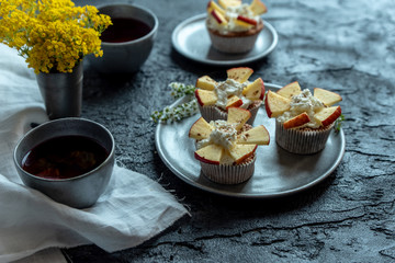 sweet muffins with yogurt and apples and tea on a dark, stone table