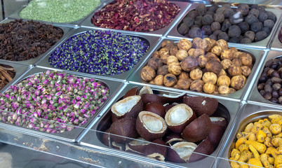 Spice and dried herb counter on the old market, Dubai, UAE. Rose, dried lemon, star anise, mint, coconut halves and hibiscus. Photo through glass. Selective focus.