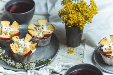 sweet muffins with yoghurt and apples and tea in silver metal dishes on a light, rustic wooden table