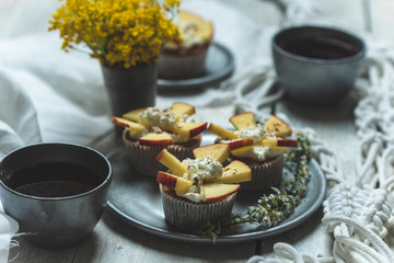 sweet muffins with yoghurt and apples and tea in silver metal dishes on a light, rustic wooden table