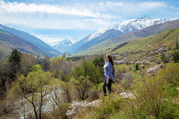 Naklejka na ściany i meble Young girl on the background of spring mountains. Beautiful mountain gorge. Nature and adventure.