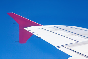 pink airplane wings on blue sky - freedom and travel concept