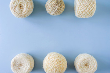 Top view of multi-colored woolen balls of yarn in a row on a blue background