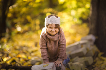 Fun girl playing in autumn park, knitted sweater