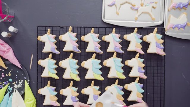 Flat lay. Step by step. Painting food glitter on top of unicorn sugar cookies with royal icing.