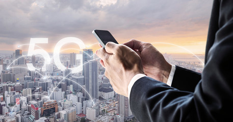 Internet networking and wireless technology. Businessman using mobile smart phone with city view in sunset, and 5G internet networking