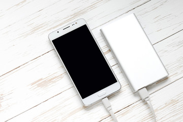 Smartphone and power bank on a white wooden background. Top view of the place for the text. Flat lay