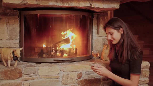 Smiling Woman Using Smartphone by Cozy Fireplace.