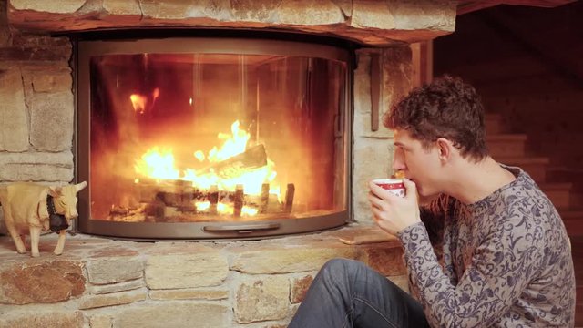Man Relaxes with a Warm Drink by the Cozy Fire.