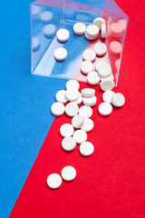 White medical pills on a two color red and blue background