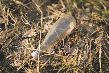 Garbage in the Park or forest, an empty bottle lying on the ground. The concept of environmental pollution, environmental problems of nature.