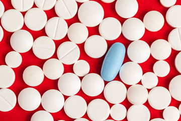 Many medicine pills close up on red background