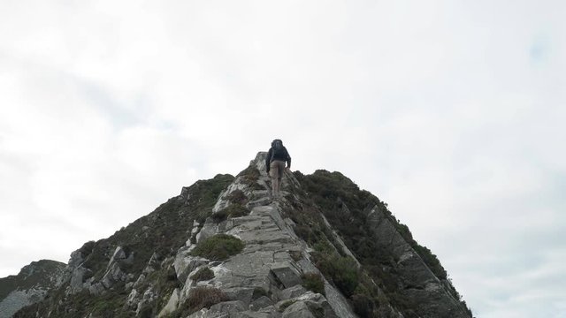 Man hiking up rugged cliff along the coast of Ireland