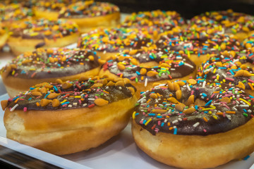 Close-up of the donuts with colorful sprinkles arranged on tray at bakery shop.