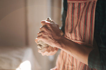 Close up of man works with clay. Male potter kneads and moistens the clay before work, toned