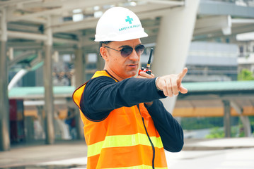 Engineer wear helmet and use radio communication for job control at construction site working
