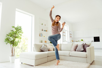 Full length body size view photo positive cheerful satisfied hipster pleasure enjoy entertainment listen soundtracks use head set  beautiful trendy striped shirt denim curly wavy hair apartment