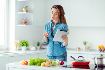 Portrait of her she nice lovely attractive focused concentrated brown-haired lady using new recipe fresh hot dish meal dinner lunch delicacy in light white interior style kitchen