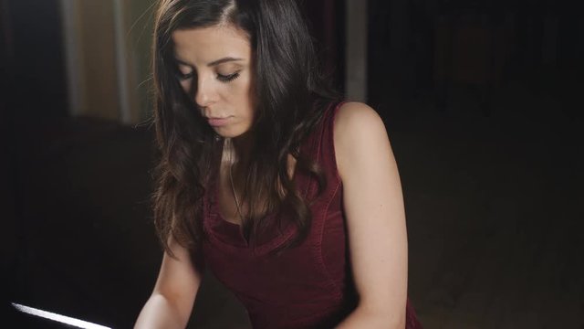 Concentrated woman in purple dress playing the piano.