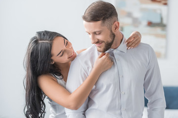 happy young woman touching collars of cheerful boyfriend in white shirt