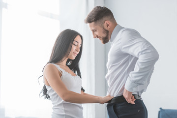 pretty brunette girl touching pants of bearded handsome man in white shirt