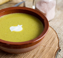 Green vegetable broccoli organic soup in ceramic bowl. Wooden plate with delicious croutons bread. Vegan, organic diet dish.