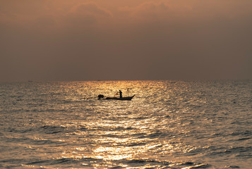 One fisherman on his boat with flash light of Sunrise
