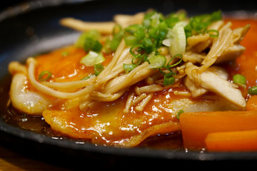 Pangasius fish steak seasoning with chili sauce, mushroom and vegetable on black plate, macro focus.