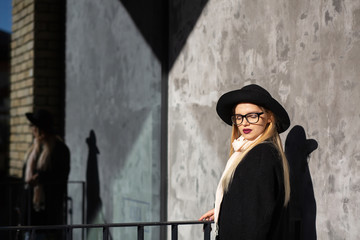 Closeup shot of fashionable blonde woman wearing glasses and hat posing in rays of sun.  Empty space