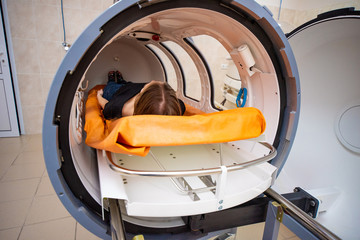 a girl in a black T-shirt lies in a hyperbaric chamber, oxygen therapy, a medical room