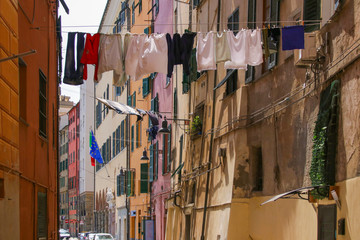 Fototapeta na wymiar A narrow alley in Savona, with clothesline, Italy flag and EU flag, Italy