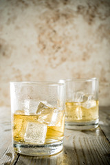 Amber Whiskey on the Rocks, alcohol drink in short glass, wooden background copy space