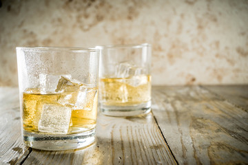 Amber Whiskey on the Rocks, alcohol drink in short glass, wooden background copy space