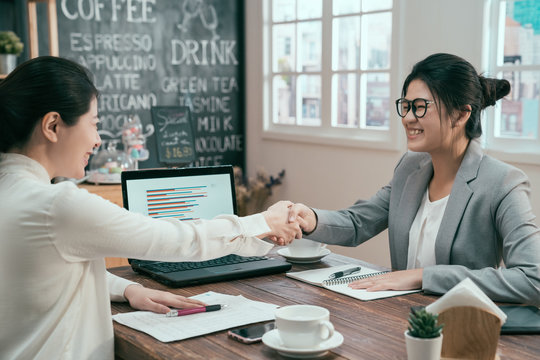 portrait of asian woman business people shaking hands finishing up meeting coffee shop. mortgage insurance broker financial advisor agent smiling to customer in cafe. two ladies make deal agreement - Powered by Adobe