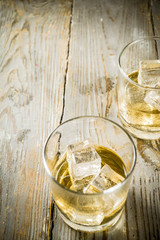 Amber Whiskey on the Rocks, alcohol drink in short glass, wooden background copy space