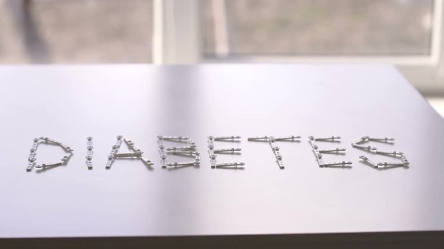 Diabetes concept. Alphabet with word DIABETES with lancets on white background. Word DIABETES with lancet on isolated white background.