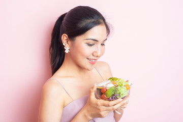 Beautiful Healthy young woman eating salad  on pink  background