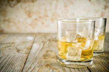 Amber Whiskey on the Rocks, alcohol drink in short glass, wooden background copy space