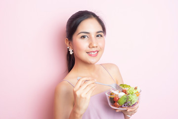 Beautiful Healthy young woman eating salad  on pink  background