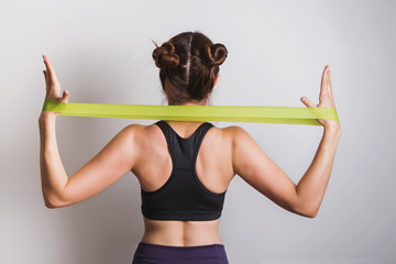Young athletic woman doing exercises with fitness rubber band
