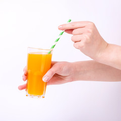 A glass with orange juice and a straw in hand in the girls. Isolate on white background.