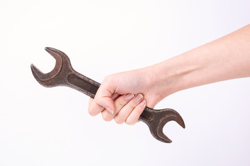 A wrench in the hand of a girl. Symbol of hard work, feminism and labor day. Isolate on white background.