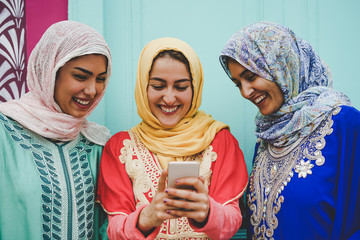 Happy Muslim women watching on mobile smart phone in the college - Arabian young girls having fun with new technologies trends apps - Millennials, Religion, culture and technology concept